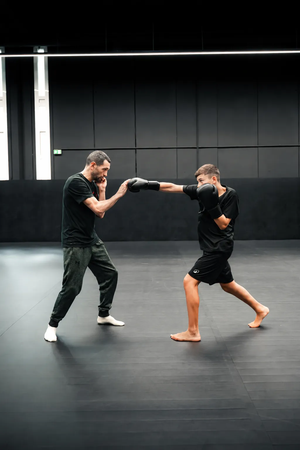 Un jeune pratiquant travaille ses frappes avec son coach sur les tatamis